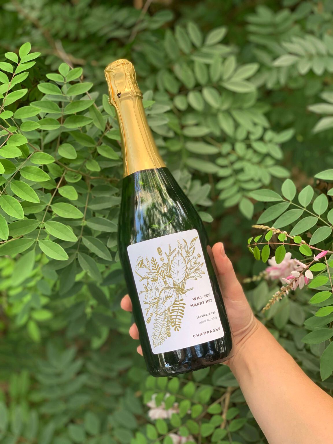 person holding a bottle of champagne with custom label