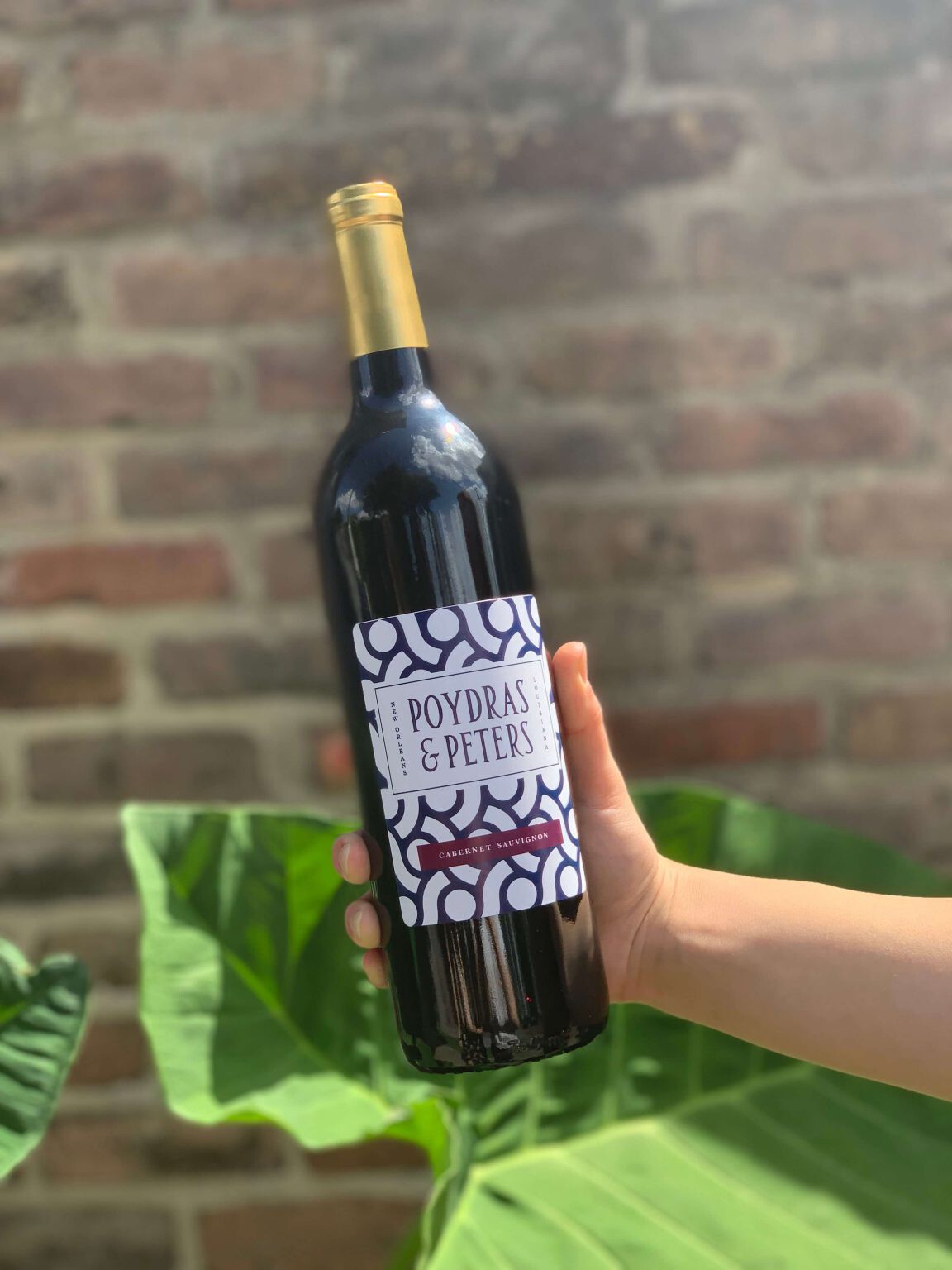 person holding a bottle of poydras & peters wine