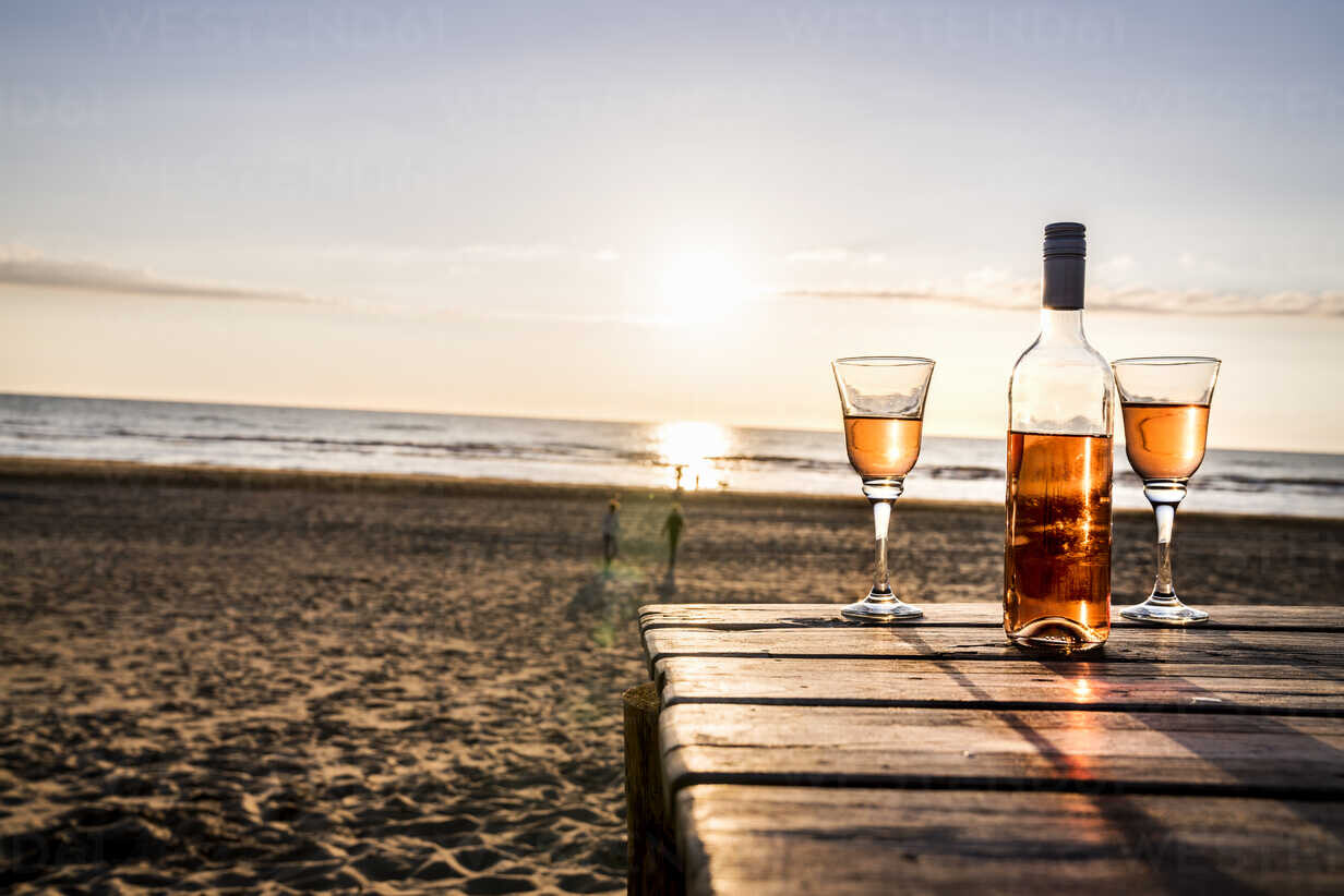 wine-bottle-and-glasses-on-boardwalk-on-the-beach-at-sunset.jpg