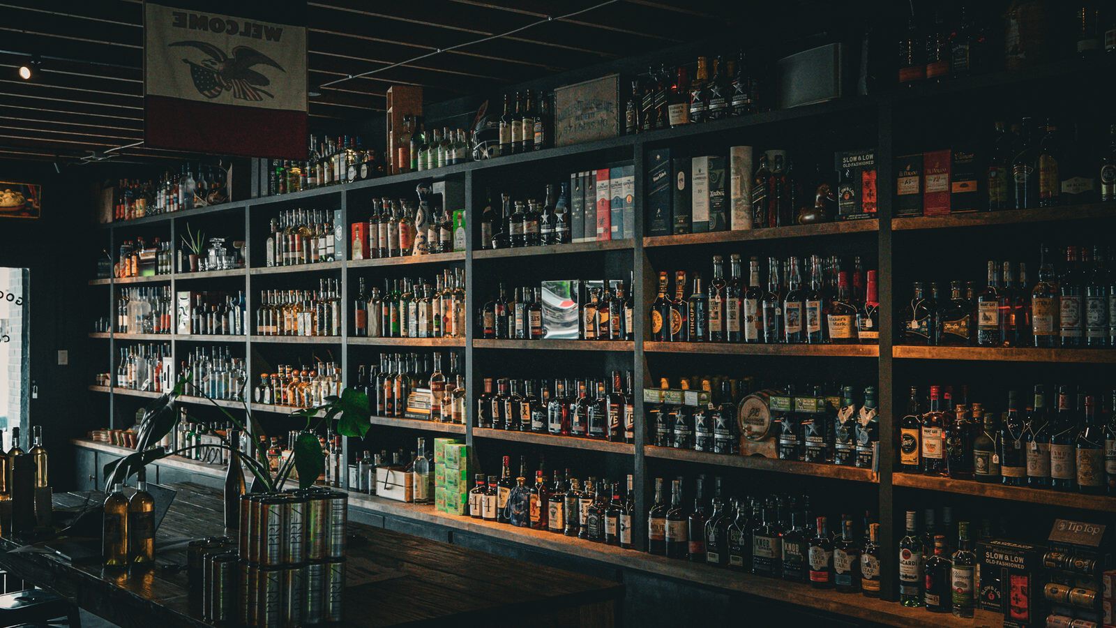 The spirits wall at Goodnight Cowboy, shelves of whiskey, agave and amaro running the length of the shop